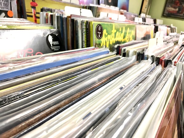 A close up photo of stacks of records in record store bins.
